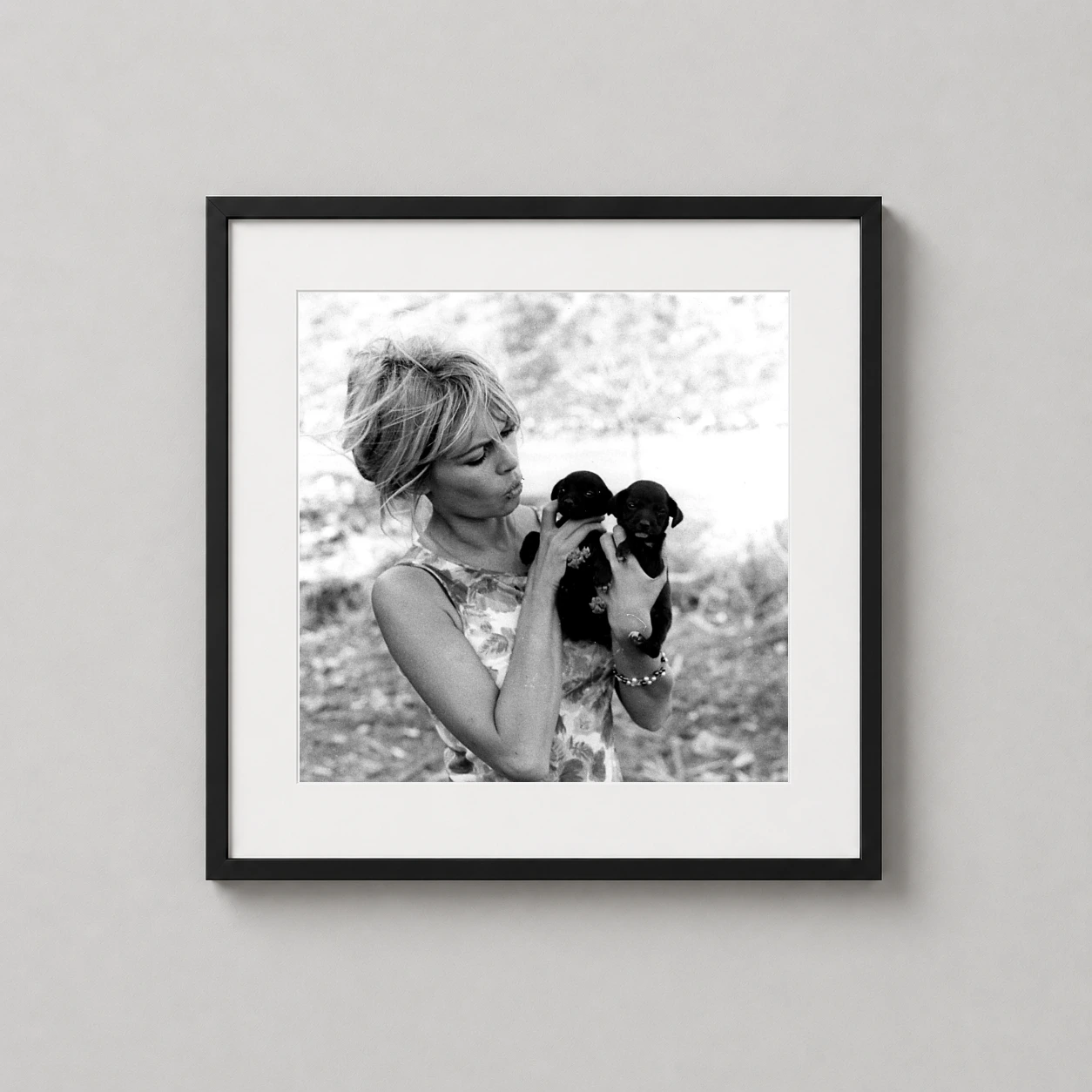 Brigitte Bardot Holding Puppies — charming black and white photograph of Brigitte Bardot puckering her