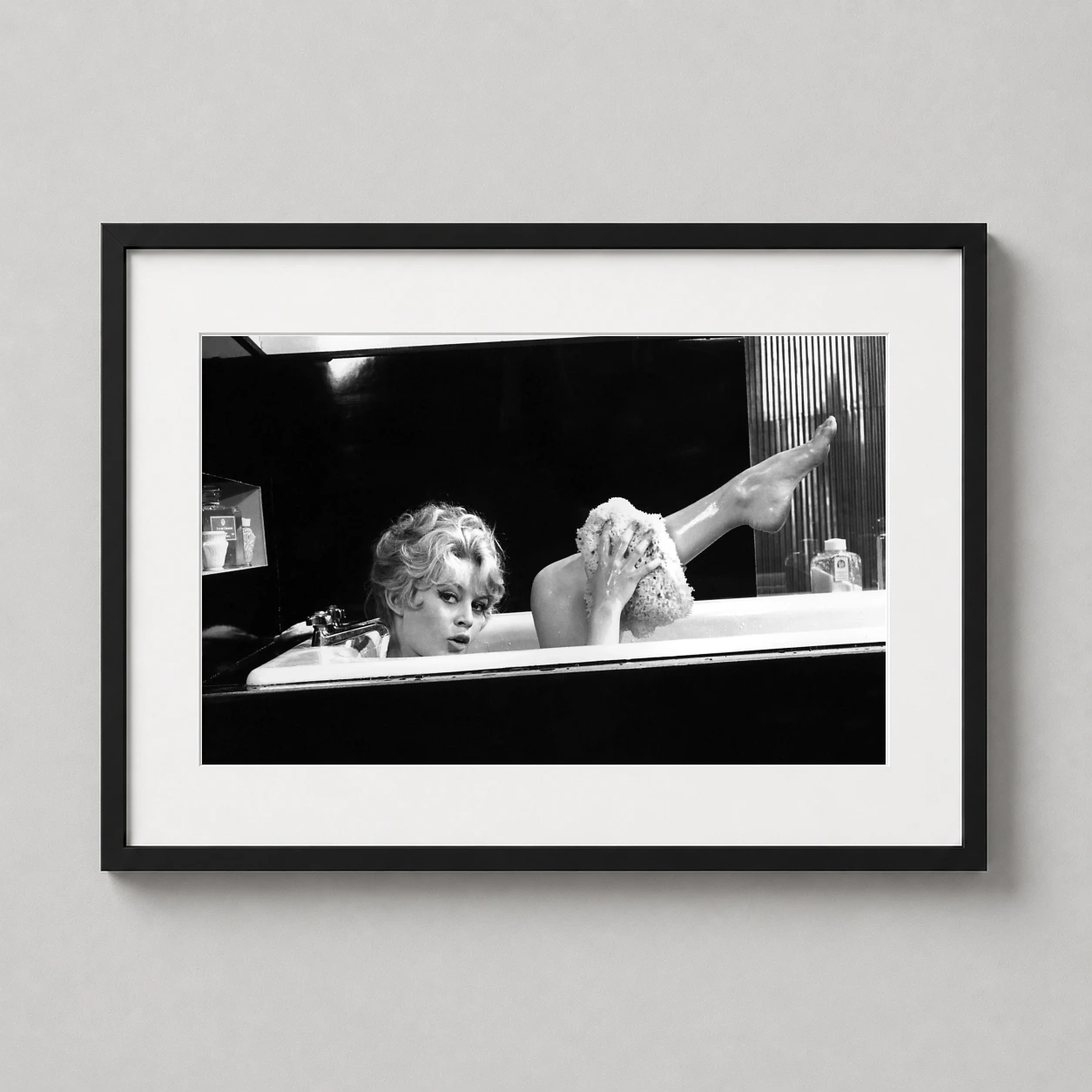 Room mockup of Brigitte Bardot Bathtub Scene 1960 Black and White Photography Print, displayed as framed wall art in a office setting as a landscape print with black and white and red tones.