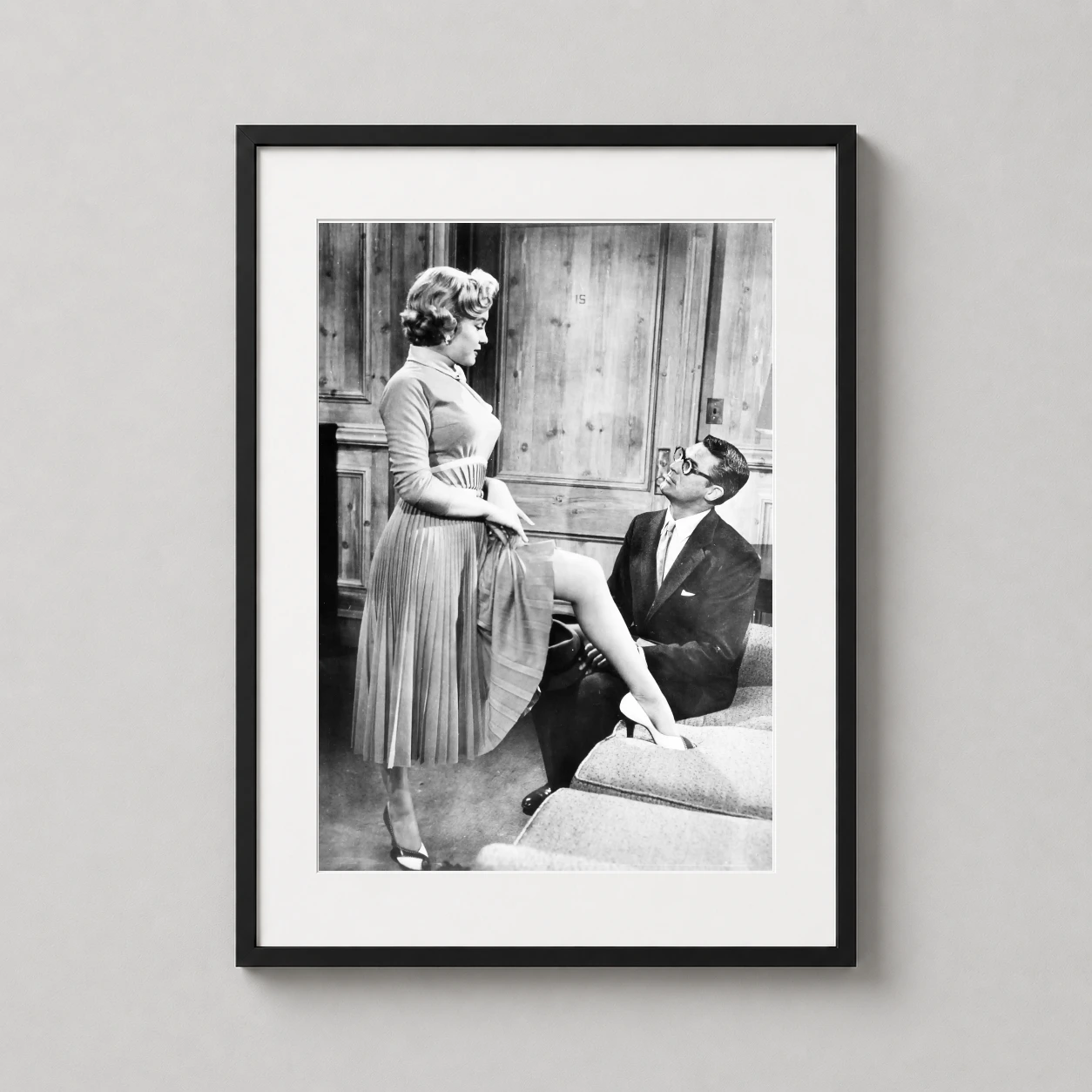 Room mockup of Cary Grant and Marilyn Monroe Monkey Business Film Poster, displayed as framed wall art in a home theater setting as a portrait print with black and white tones.