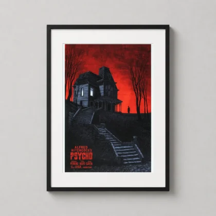 A framed bates house art print hangs on a modern wall, showcasing the eerie red and black Psycho movie landscape.