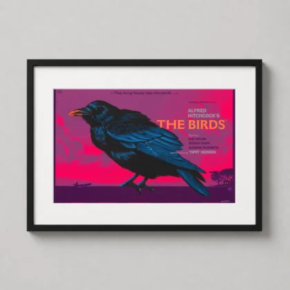 A framed The Birds art print by Laurent Durieux hanging in a moody home office alongside classic cinema collectibles.