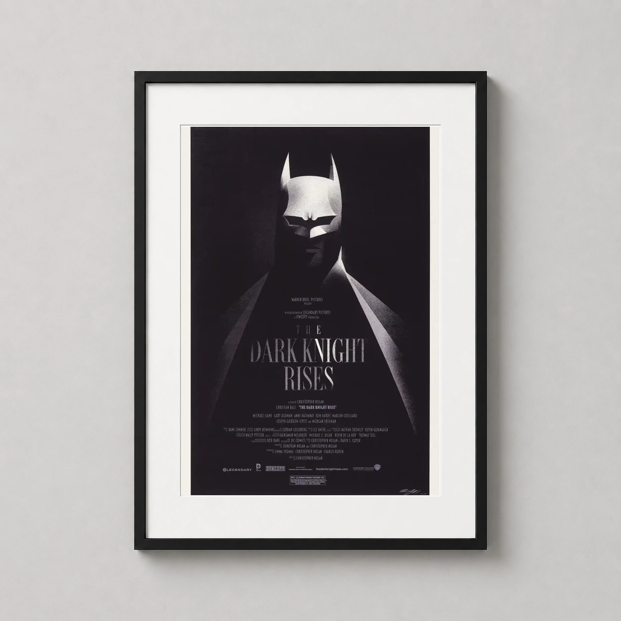 Room mockup of Batman The Dark Knight Rises Olly Moss Mondo Minimalist Movie Poster, displayed as framed wall art in a home theater setting as a portrait print with black and white tones.