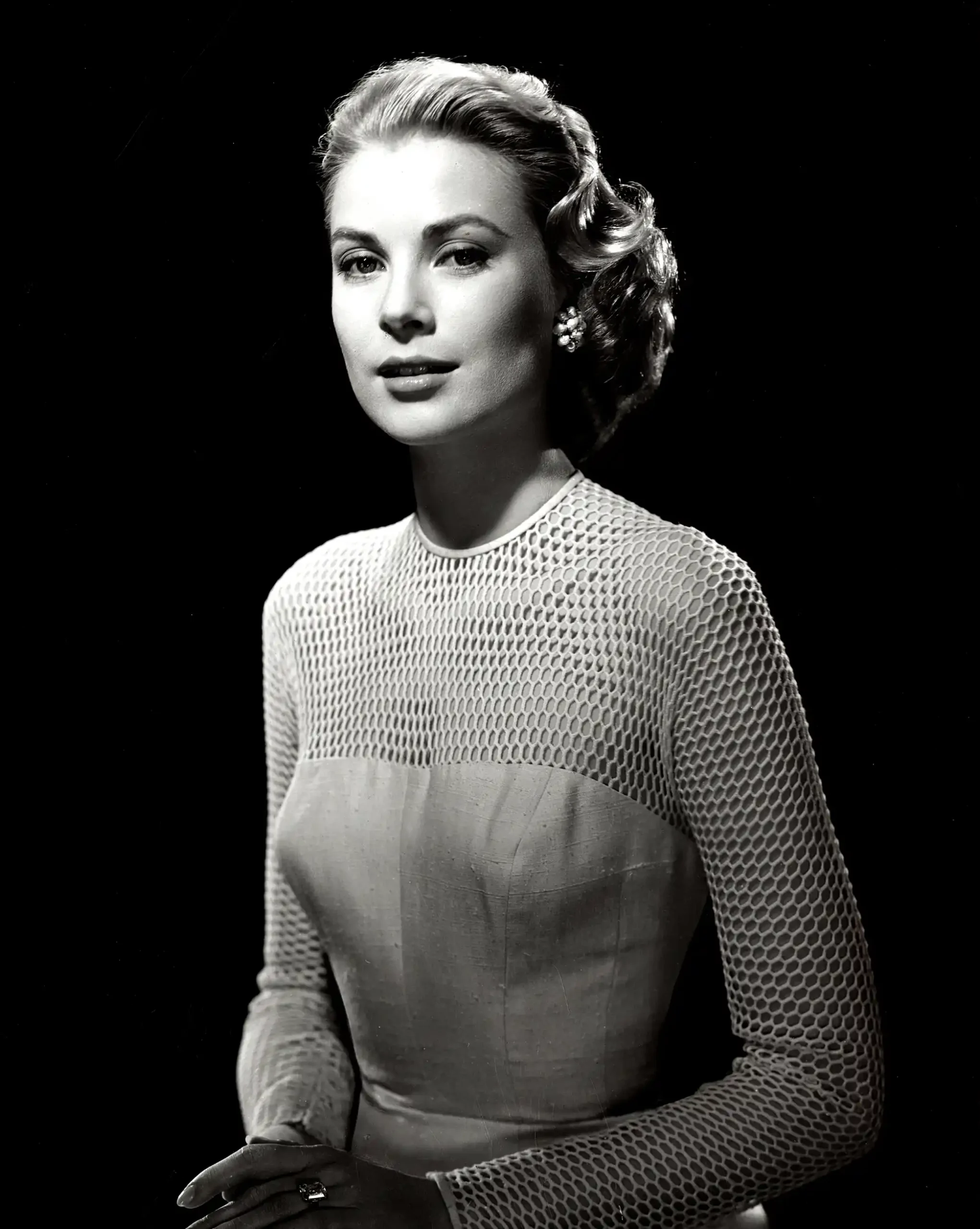 Grace Kelly studio poster showing a 1955 portrait with mesh sleeves and a pale bodice.
