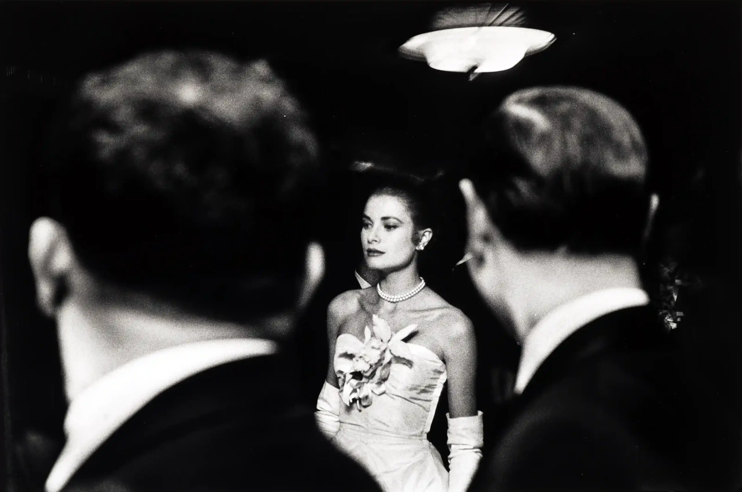 Kelly New York poster showing Grace Kelly in 1955 framed by dark foreground figures at an evening event.