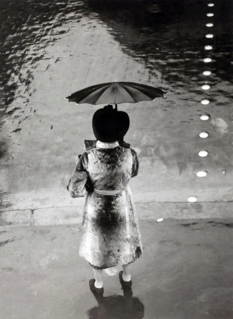 Brassai poster showing a woman with an umbrella on Rue de Rivoli in 1937.