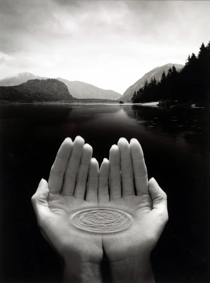 Jerry Uelsmann poster showing hands rising from a still lake, 2026