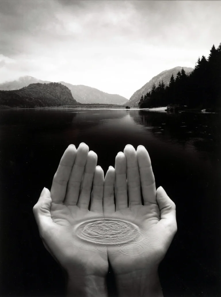 Clean artwork view of Lake Hands Poster, Jerry Uelsmann 2026 Photography Print. Lake Hands Poster (2003) presents hands emerging from a quiet lake in a dreamlike black-and-white scene with the photographer and subject kept clear.